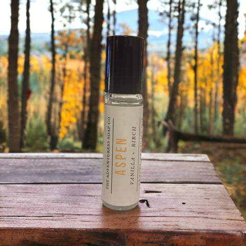 Aspen Perfume Oil on wooden table with aspen trees in background.