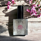 Kyoto Eau de Parfum laying on wooden table with cherry blossoms
