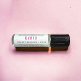Kyoto Perfume Oil with cherry blossom and musk laying on pink backdrop