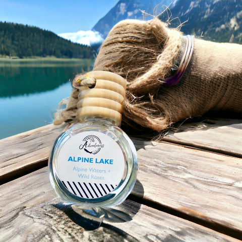 Alpine Lake Car Diffuser displayed on a wooden table with lake and mountains in background.