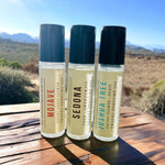 Mojave, Sedona and Joshua Tree Perfume Oils standing on wooden table with desert scenery in background