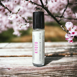 Kyoto Perfume Oil laying on wooden table with cherry blossoms 