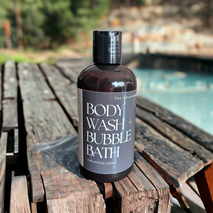 Hot Spring Body Wash and Bubble Bath sitting on wooden table with hot spring in background