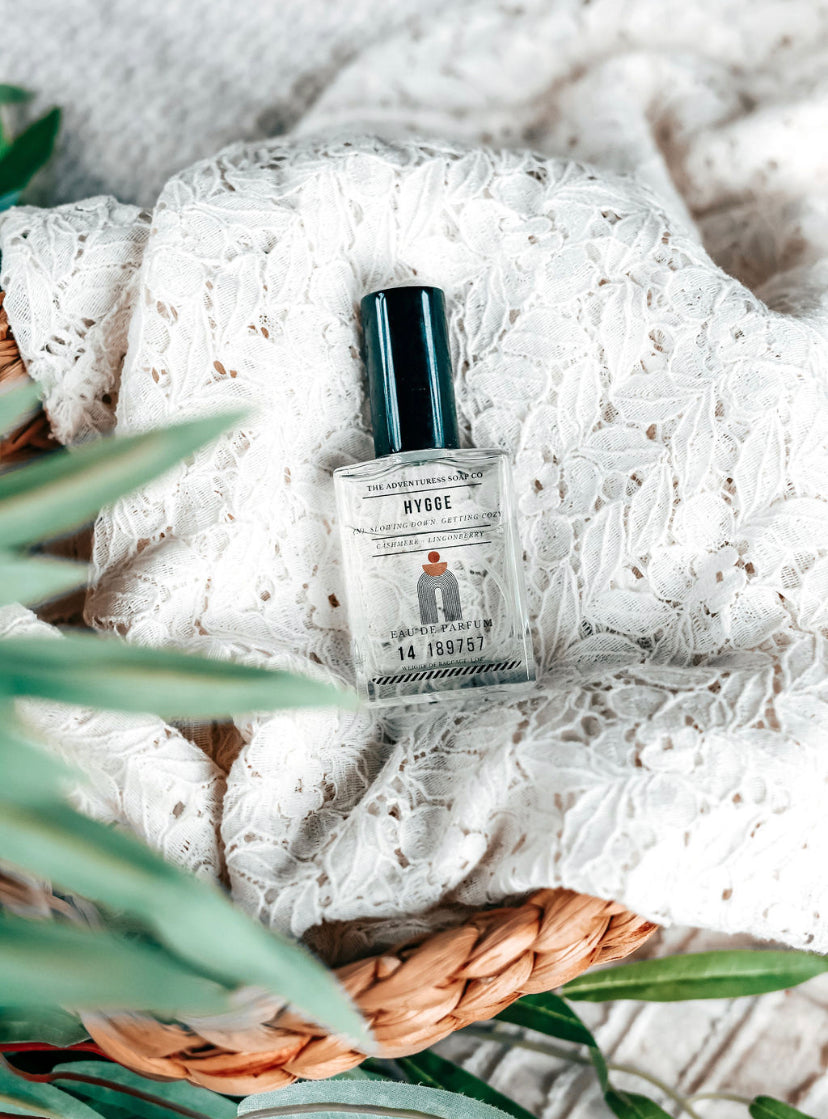 Hygge Eau de Parfum laying on lacy white sheet in basket
