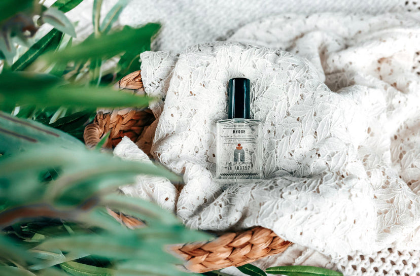 Hygge Eau de Parfum laying on lacy white sheet in basket