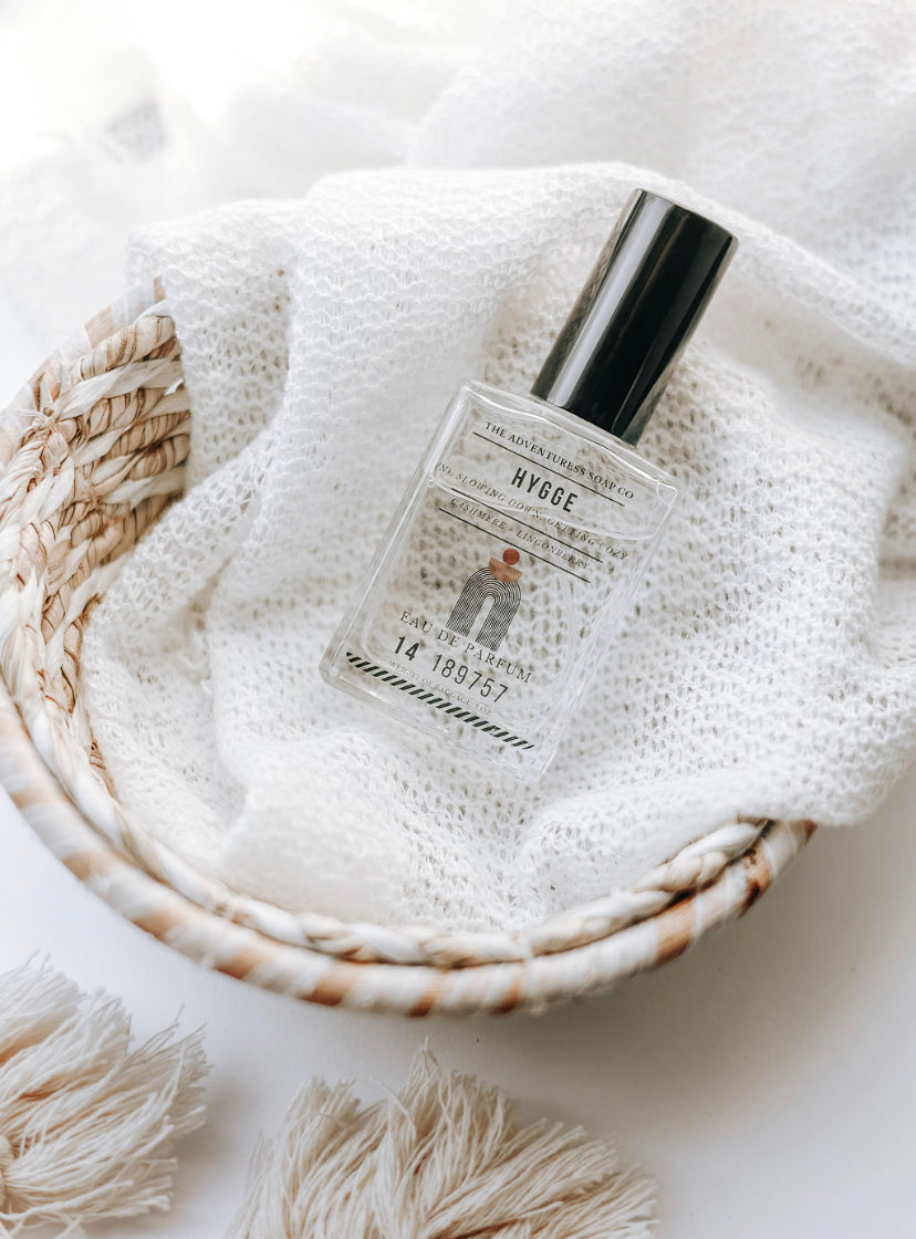 Hygge Eau de Parfum laying on white sheet in boho basket