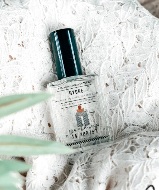 Hygge Eau de Parfum laying on lacy white sheet