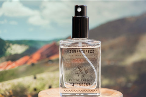 Adventuress Eau de Parfum in front of a picture of Red Rocks, Colorado.
