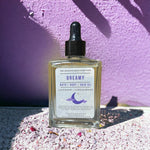 Dreamy Bath Body Hair Oil standing in front of lilac wall 