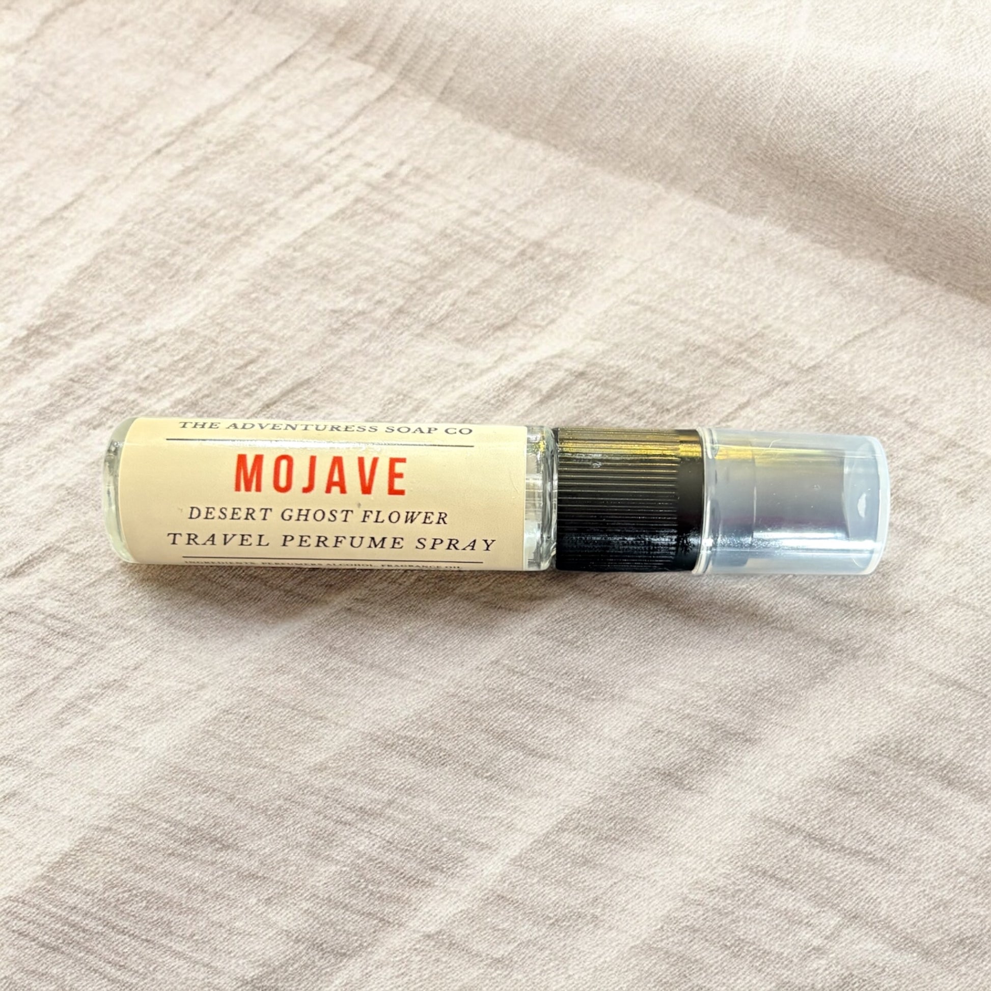 Travel perfume spray bottle labeled 'Mojave' on a textured beige surface