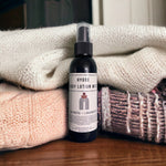 Hygge Lotion Mist on dresser surrounded by cozy textiles 