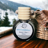 Breckenridge Car Diffuser on wooden table with snowy mountains in background.