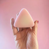 Hand holding small pink mountain shaped soap in front of pink backdrop