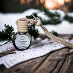 Evergreen Frost Car Diffuser on picnic table with beige tablecloth and pine tree branches