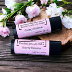 Cherry Blossom Lip Balm on wooden table with pink blossoms in backdrop