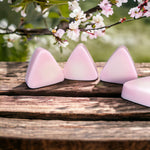 Small pink mountain shaped soaps in front of cherry blossoms