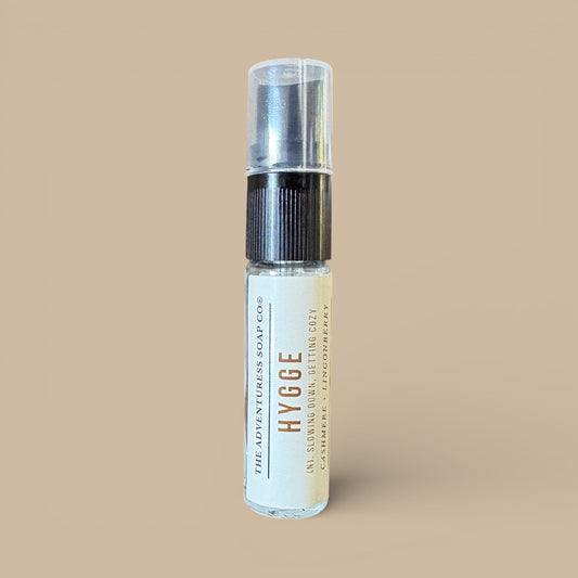 Clear spray bottle labeled 'Hygge” on a beige background