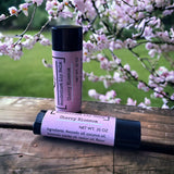 Cherry Blossom lip balm standing on table with green park and cherry blossoms in background