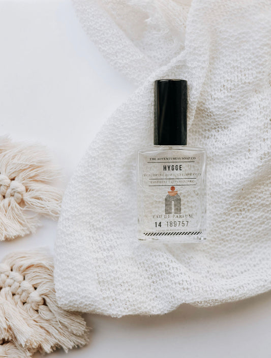Hygge Eau de Parfum laying on white lacy sheet with boho accents 