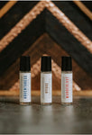 adventuress perfume oil, wanderlust perfume oil, and hygge perfume oils laid in front of rustic background