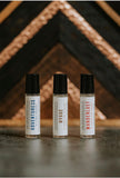 adventuress perfume oil, wanderlust perfume oil, and hygge perfume oils laid in front of rustic background